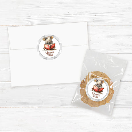 A set of thank you stickers adorned with a watercolor koala reading a red book, set against a neutral buffalo plaid background. Text reads "thank you," Perfect for literary or woodland-themed celebrations.