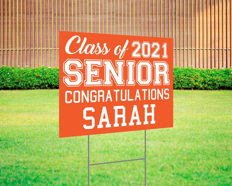 Graduation yard sign featuring bold varsity-style SENIOR lettering, custom class year, and congratulations message. Printed on durable Coreplast plastic, available in custom colors and single or double-sided print, perfect for high school and college graduates. orange