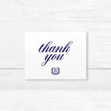 Thank you card with navy monogram crest and formal calligraphy, printed on white textured paper for traditional wedding stationery