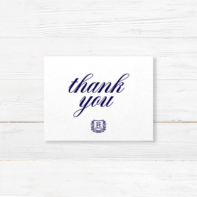 Thank you card with navy monogram crest and formal calligraphy, printed on white textured paper for traditional wedding stationery