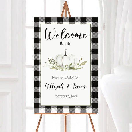 A white pumpkin baby shower welcome sign with a white pumpkin and plaid border. The design features neutral colors and seasonal text.