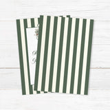 Winter wedding invitation featuring dark green and ivory vertical stripes, a white panel, floral monogram crest with greenery and roses, and elegant script and serif fonts for a formal winter wedding. - back side