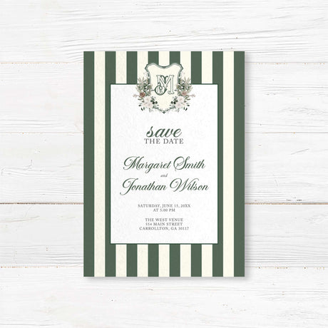 Save the Date card for winter wedding featuring dark green and ivory vertical stripes, centered white panel, floral crest monogram, and romantic script and serif fonts.
